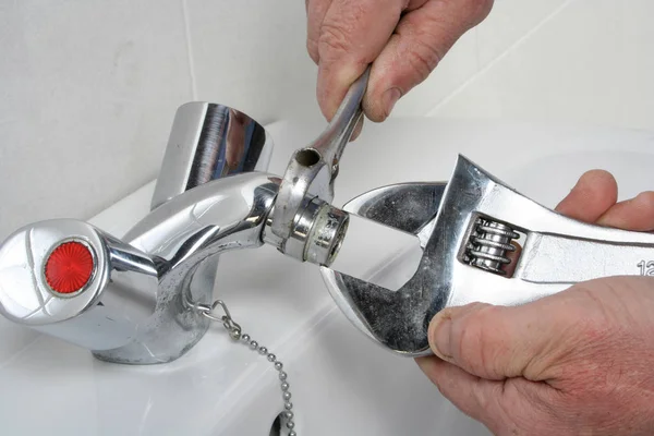 Loodgieter herstellen van een kraan in een badkamer — Stockfoto