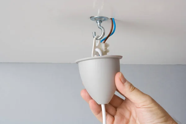 Electrician mounting a light fixture for a ceiling lamp.