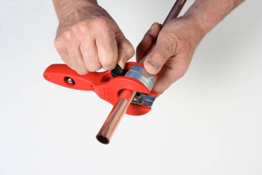 Tesisatçı özel bir aletle bakır boru kesme.