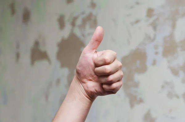 Başparmak yukarıya üstünde düzensiz duvar bir arka plan