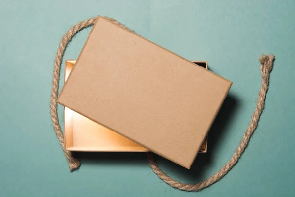 Rustik hediye kutusu yeşil boyalı tablo üzerinde parlayan. Paketli hediye kutusu kahverengi kağıt ve sicim geri dönüştürülmüş. Kavramlardır tatil hediye, Eko Dostu ambalaj, rustik tarzı hediye sarma.