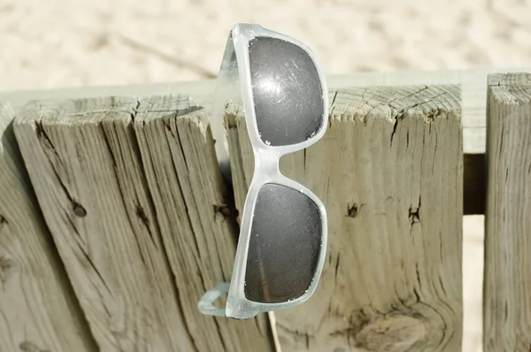 Weathered sunglasses on the beach, close up design. Touristic seaside shore view on natural wooden background for wallpaper, tour destination advertisiment