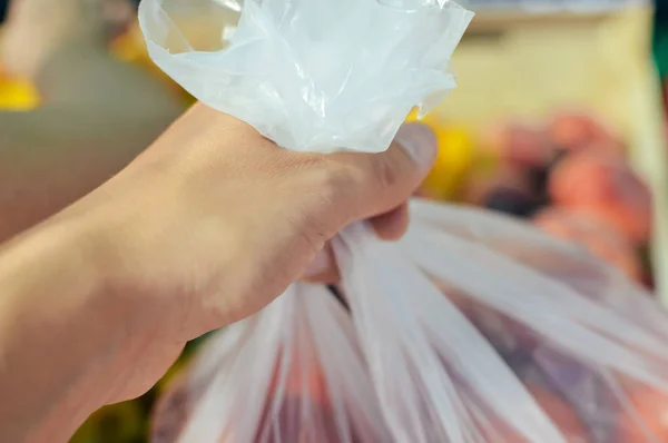 Close up sulla mano umana azienda sceglie pomodori negozio alimentare sfondo del mercato — Foto Stock