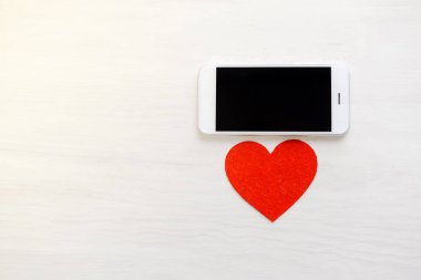 Üstten Görünüm ahşap Resepsiyon arka plan üzerinde akıllı telefon ve sevgi kalpleri üzerinde. Düz yatıyordu stil alanı portre resmi Kopyala