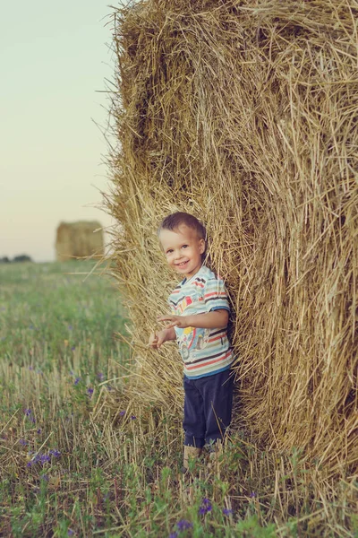 Dziecko w pobliżu słomy na polu — Zdjęcie stockowe