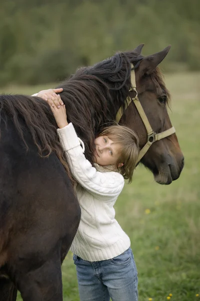 Menina bonito abraçando pescoço do cavalo bonito e olhando para a câmera. Retrato de estilo de vida — Fotografia de Stock
