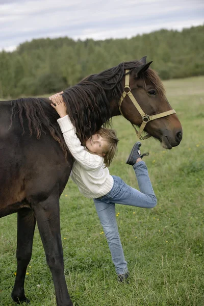 Menina bonito abraçando pescoço do cavalo bonito e olhando para a câmera. Retrato de estilo de vida — Fotografia de Stock