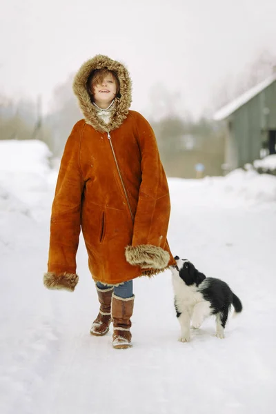 La niña en el abrigo de piel de su madre caminando por la calle y al lado del cachorro — Foto de Stock