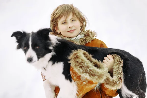 Niña niña en invierno sostiene un negro y blanco borde collie perro — Foto de Stock