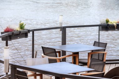 Lokantanın içinde masalar ve mavi su üzerindeki sandalyeler var.