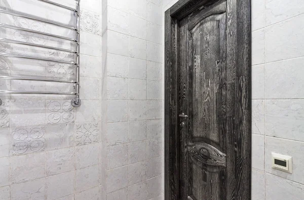 Classical closed wooden black oak door in white tiled mosaic wall of the bathroom — Stock fotografie