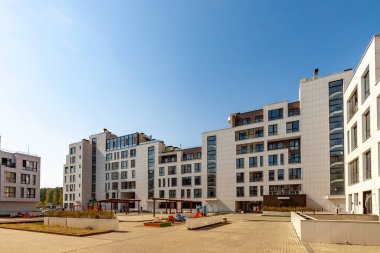 Yeni yerleşim alanındaki çocuk parkı ile birlikte birkaç tane düşük katlı inşaat binası var. Mavi gökyüzü güneşli arka planda. Kentsel gelişim konsepti resmi