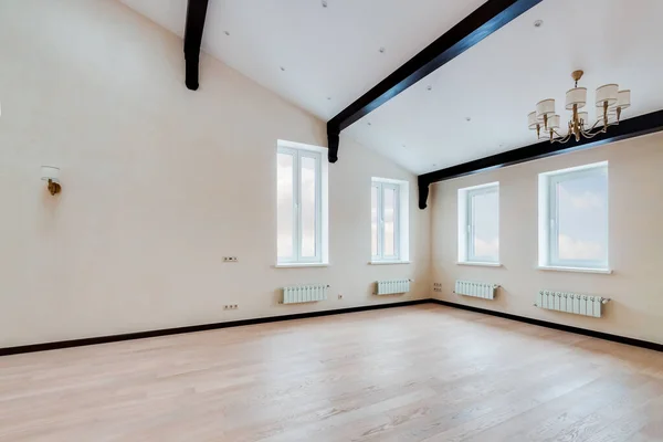 Пустой светлый зал с широким белым окном и люстрой и деревянными черными балками на потолке — стоковое фото