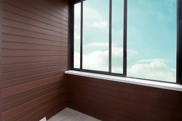 Looking light blue cloud sky through opened large clean glass sliding window brown plastic or wood balcony.