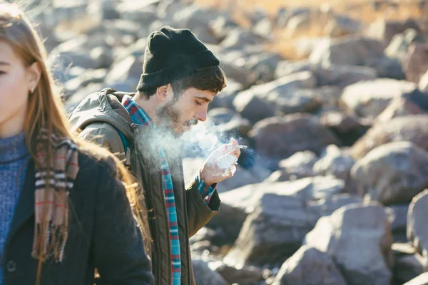 Стильный портрет курящего парня, гуляющего с девушкой по скалистому берегу моря . — стоковое фото