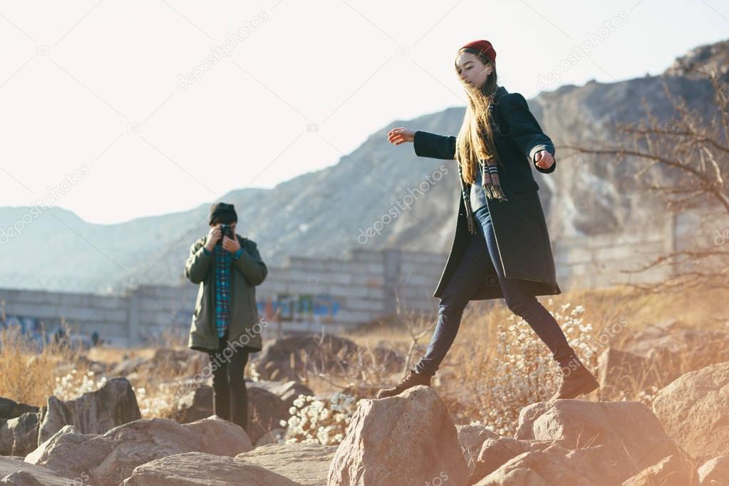 Beautiful and stylish couple are photographed on a rocky beach. Couple dressed in jackets, hats and boots