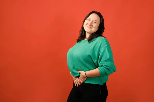 Happy plus size positive woman. Happy body positive concept. I love my body. Attractive overweight woman posing on camera in the studio on a colored background. Girl wearing a green sweater