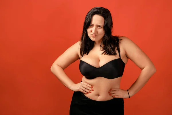 Happy plus size positive woman. Happy body positive concept. I love my body. Attractive overweight woman posing on camera in the studio on a colored background. Girl is wearing a black bra