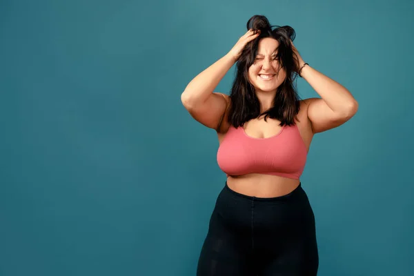 Happy plus size positive woman. Happy body positive concept. I love my body. Attractive overweight woman posing on camera in the studio on a colored background. Girl is wearing a coral bra