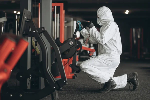 Cleaning and Disinfection in crowded places amid the coronavirus epidemic Gym cleaning and disinfection Infection prevention and control of epidemic. Protective suit and mask and spray bag