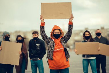 Koronavirüs karşıtı protestoları ve koronavirüs ve insan haklarıyla ilgili karantina toplantısını protesto etmek için posterlerle gelen maskeli bir grup insan. Kopyalama alanı