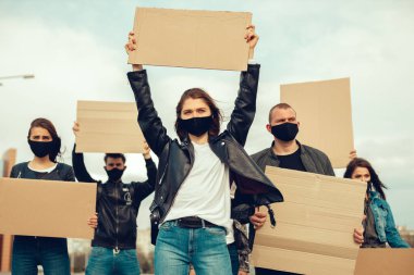 Koronavirüs karşıtı protestoları ve koronavirüs ve insan haklarıyla ilgili karantina toplantısını protesto etmek için posterlerle gelen maskeli bir grup insan. Kopyalama alanı
