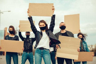 Koronavirüs karşıtı protestoları ve koronavirüs ve insan haklarıyla ilgili karantina toplantısını protesto etmek için posterlerle gelen maskeli bir grup insan. Kopyalama alanı