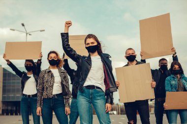 Koronavirüs karşıtı protestoları ve koronavirüs ve insan haklarıyla ilgili karantina toplantısını protesto etmek için posterlerle gelen maskeli bir grup insan. Kopyalama alanı