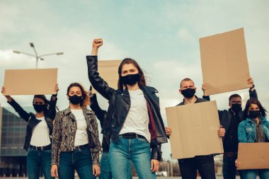 Koronavirüs karşıtı protestoları ve koronavirüs ve insan haklarıyla ilgili karantina toplantısını protesto etmek için posterlerle gelen maskeli bir grup insan. Kopyalama alanı