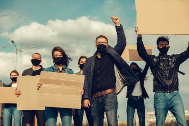 Koronavirüs karşıtı protestoları ve koronavirüs ve insan haklarıyla ilgili karantina toplantısını protesto etmek için posterlerle gelen maskeli bir grup insan. Kopyalama alanı