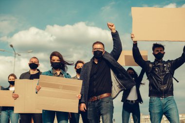 Koronavirüs karşıtı protestoları ve koronavirüs ve insan haklarıyla ilgili karantina toplantısını protesto etmek için posterlerle gelen maskeli bir grup insan. Kopyalama alanı