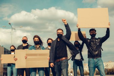 Koronavirüs karşıtı protestoları ve koronavirüs ve insan haklarıyla ilgili karantina toplantısını protesto etmek için posterlerle gelen maskeli bir grup insan. Kopyalama alanı