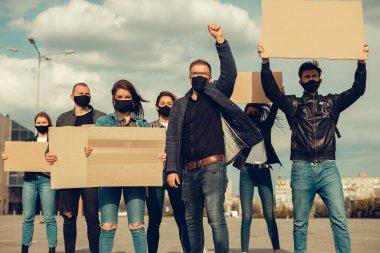 Koronavirüs karşıtı protestoları ve koronavirüs ve insan haklarıyla ilgili karantina toplantısını protesto etmek için posterlerle gelen maskeli bir grup insan. Kopyalama alanı