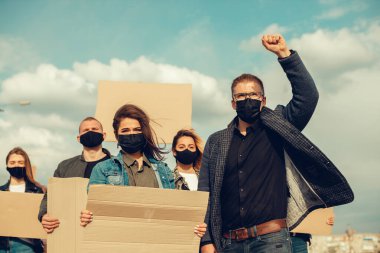 Koronavirüs karşıtı protestoları ve koronavirüs ve insan haklarıyla ilgili karantina toplantısını protesto etmek için posterlerle gelen maskeli bir grup insan. Kopyalama alanı