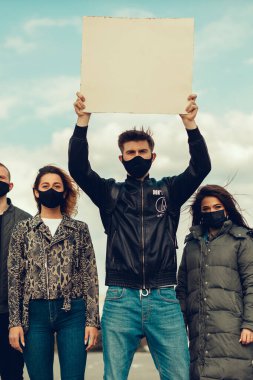 Koronavirüs karşıtı protestoları ve koronavirüs ve insan haklarıyla ilgili karantina toplantısını protesto etmek için posterlerle gelen maskeli bir grup insan. Kopyalama alanı