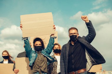Koronavirüs karşıtı protestoları ve koronavirüs ve insan haklarıyla ilgili karantina toplantısını protesto etmek için posterlerle gelen maskeli bir grup insan. Kopyalama alanı