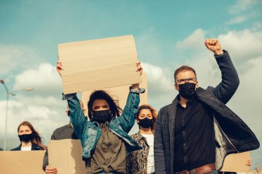 Koronavirüs karşıtı protestoları ve koronavirüs ve insan haklarıyla ilgili karantina toplantısını protesto etmek için posterlerle gelen maskeli bir grup insan. Kopyalama alanı