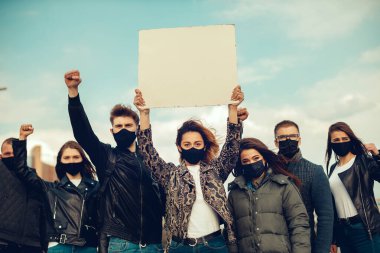 Koronavirüs karşıtı protestoları ve koronavirüs ve insan haklarıyla ilgili karantina toplantısını protesto etmek için posterlerle gelen maskeli bir grup insan. Kopyalama alanı