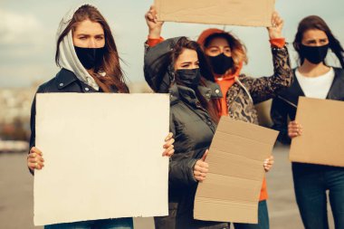 Koronavirüs karşıtı protestoları ve koronavirüs ve insan haklarıyla ilgili karantina toplantısını protesto etmek için posterlerle gelen maskeli bir grup insan. Kopyalama alanı