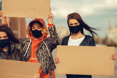 Koronavirüs karşıtı protestoları ve koronavirüs ve insan haklarıyla ilgili karantina toplantısını protesto etmek için posterlerle gelen maskeli bir grup insan. Kopyalama alanı