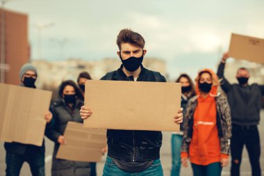 Koronavirüs karşıtı protestoları ve koronavirüs ve insan haklarıyla ilgili karantina toplantısını protesto etmek için posterlerle gelen maskeli bir grup insan. Kopyalama alanı