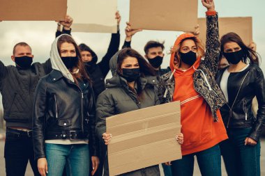 Koronavirüs karşıtı protestoları ve koronavirüs ve insan haklarıyla ilgili karantina toplantısını protesto etmek için posterlerle gelen maskeli bir grup insan. Kopyalama alanı