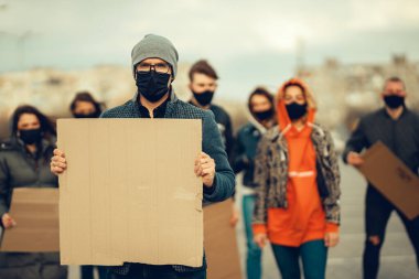 Koronavirüs karşıtı protestoları ve koronavirüs ve insan haklarıyla ilgili karantina toplantısını protesto etmek için posterlerle gelen maskeli bir grup insan. Kopyalama alanı