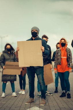 Koronavirüs karşıtı protestoları ve koronavirüs ve insan haklarıyla ilgili karantina toplantısını protesto etmek için posterlerle gelen maskeli bir grup insan. Kopyalama alanı