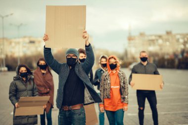 Koronavirüs karşıtı protestoları ve koronavirüs ve insan haklarıyla ilgili karantina toplantısını protesto etmek için posterlerle gelen maskeli bir grup insan. Kopyalama alanı
