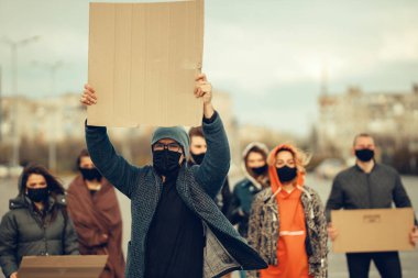 Koronavirüs karşıtı protestoları ve koronavirüs ve insan haklarıyla ilgili karantina toplantısını protesto etmek için posterlerle gelen maskeli bir grup insan. Kopyalama alanı