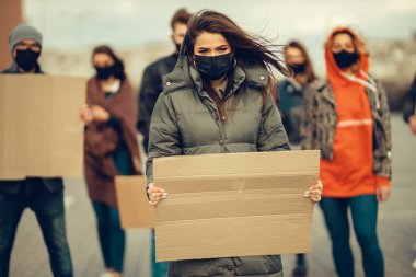 Koronavirüs karşıtı protestoları ve koronavirüs ve insan haklarıyla ilgili karantina toplantısını protesto etmek için posterlerle gelen maskeli bir grup insan. Kopyalama alanı