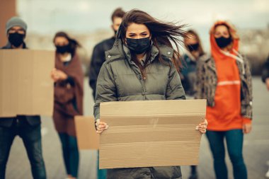 Koronavirüs karşıtı protestoları ve koronavirüs ve insan haklarıyla ilgili karantina toplantısını protesto etmek için posterlerle gelen maskeli bir grup insan. Kopyalama alanı