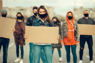 Koronavirüs karşıtı protestoları ve koronavirüs ve insan haklarıyla ilgili karantina toplantısını protesto etmek için posterlerle gelen maskeli bir grup insan. Kopyalama alanı