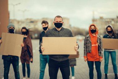 Koronavirüs karşıtı protestoları ve koronavirüs ve insan haklarıyla ilgili karantina toplantısını protesto etmek için posterlerle gelen maskeli bir grup insan. Kopyalama alanı